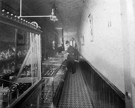 Interior photo from the 1890s of the American Jewelry Company located at 413 Harrison Avenue. Ruben Fogel is on the left.